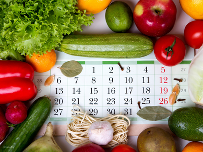 Viele verschiedene Obst und Gemüsesorten liegen auf einem Kalender.